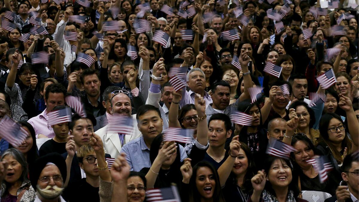 Newly sworn-in Americans wave flags after taking the oath of citizenship.