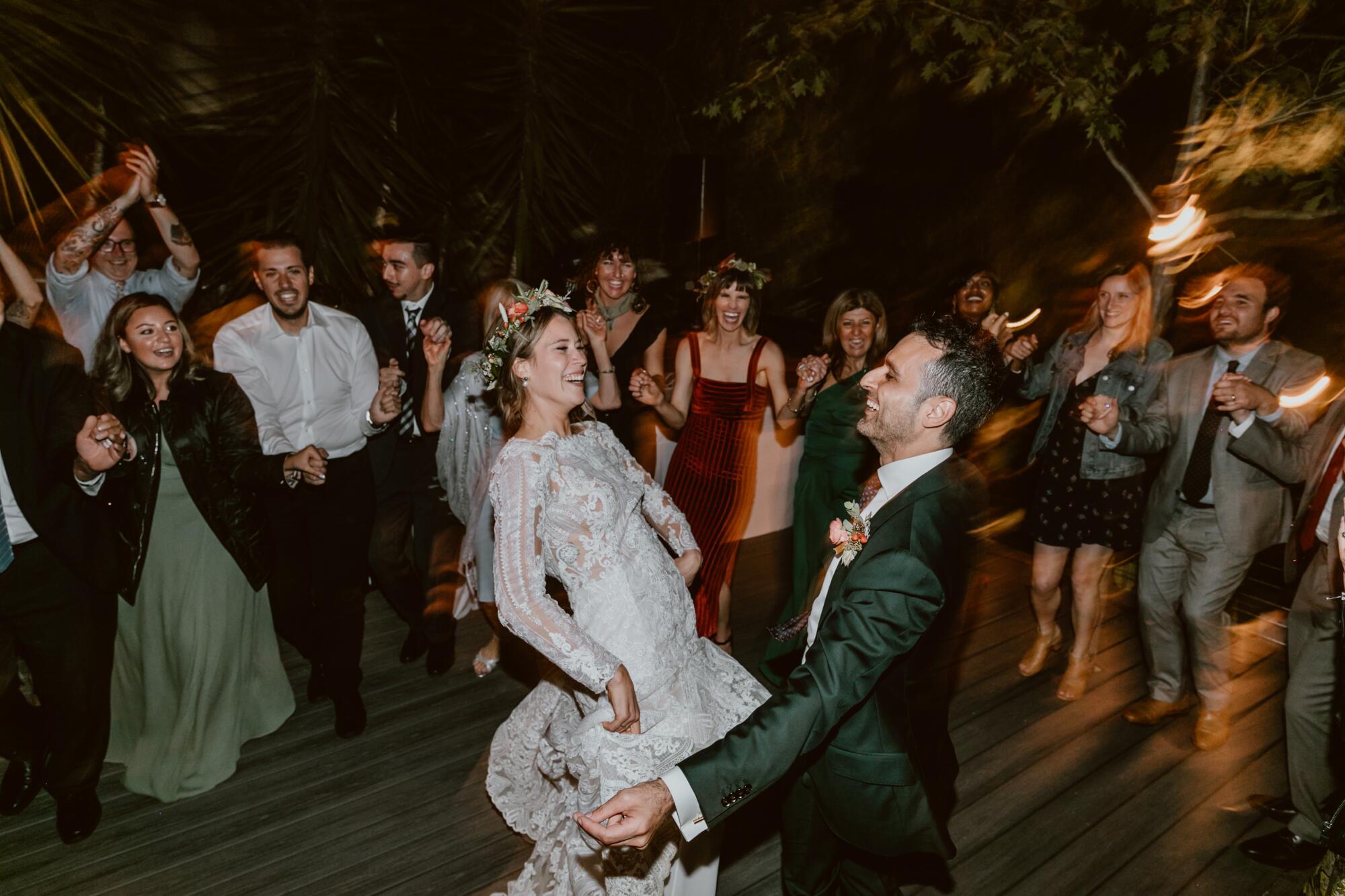 A couple dancing at their wedding as guests stand around watching them