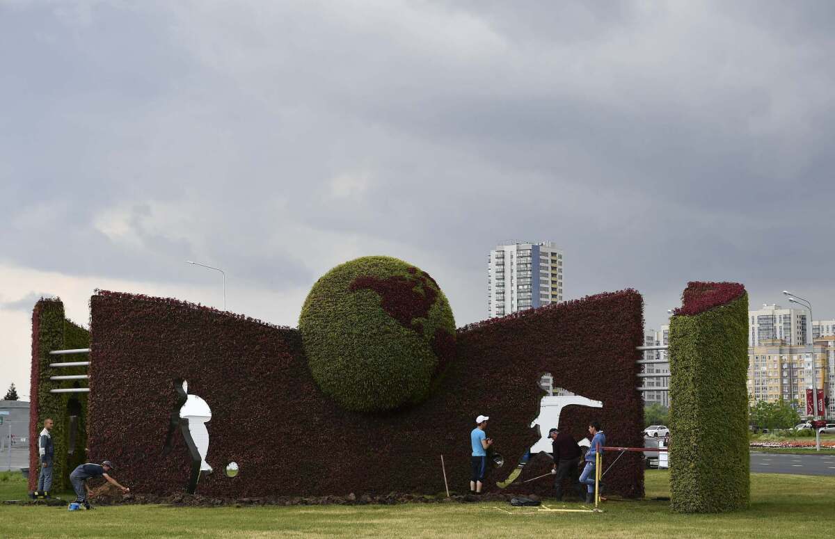 Men work by a hedge featuring footballers in Kazan, Russia, on June 27, 2017 on the eve of the Russia 2017 FIFA Confederations Cup football semi-final match Portugal vs Chile. / AFP PHOTO / Yuri CORTEZYURI CORTEZ/AFP/Getty Images ** OUTS - ELSENT, FPG, CM - OUTS * NM, PH, VA if sourced by CT, LA or MoD **