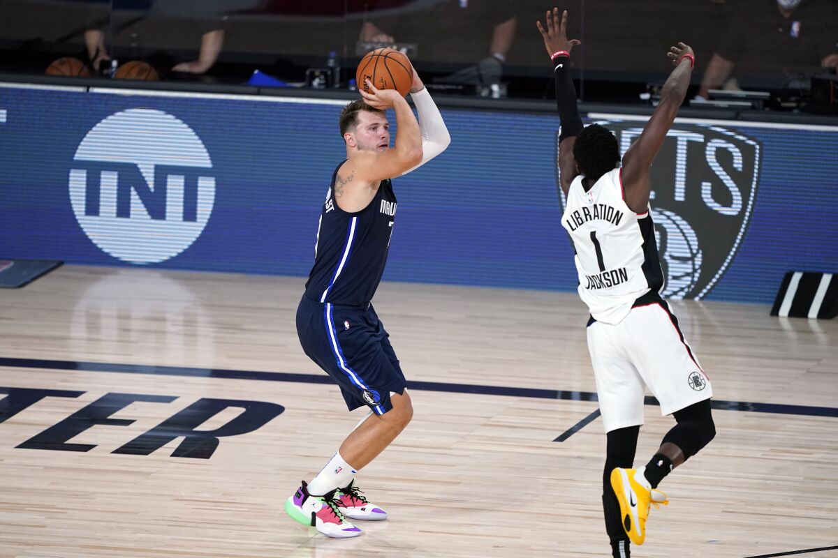 Dallas Mavericks' Luka Doncic (77) shoots his game-winning 3-point basket as Los Angeles Clippers' Reggie Jackson.
