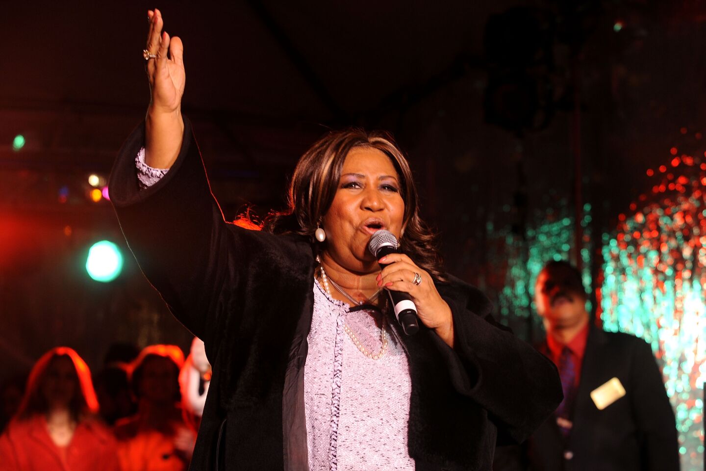Aretha Franklin performs while three people stand behind her.
