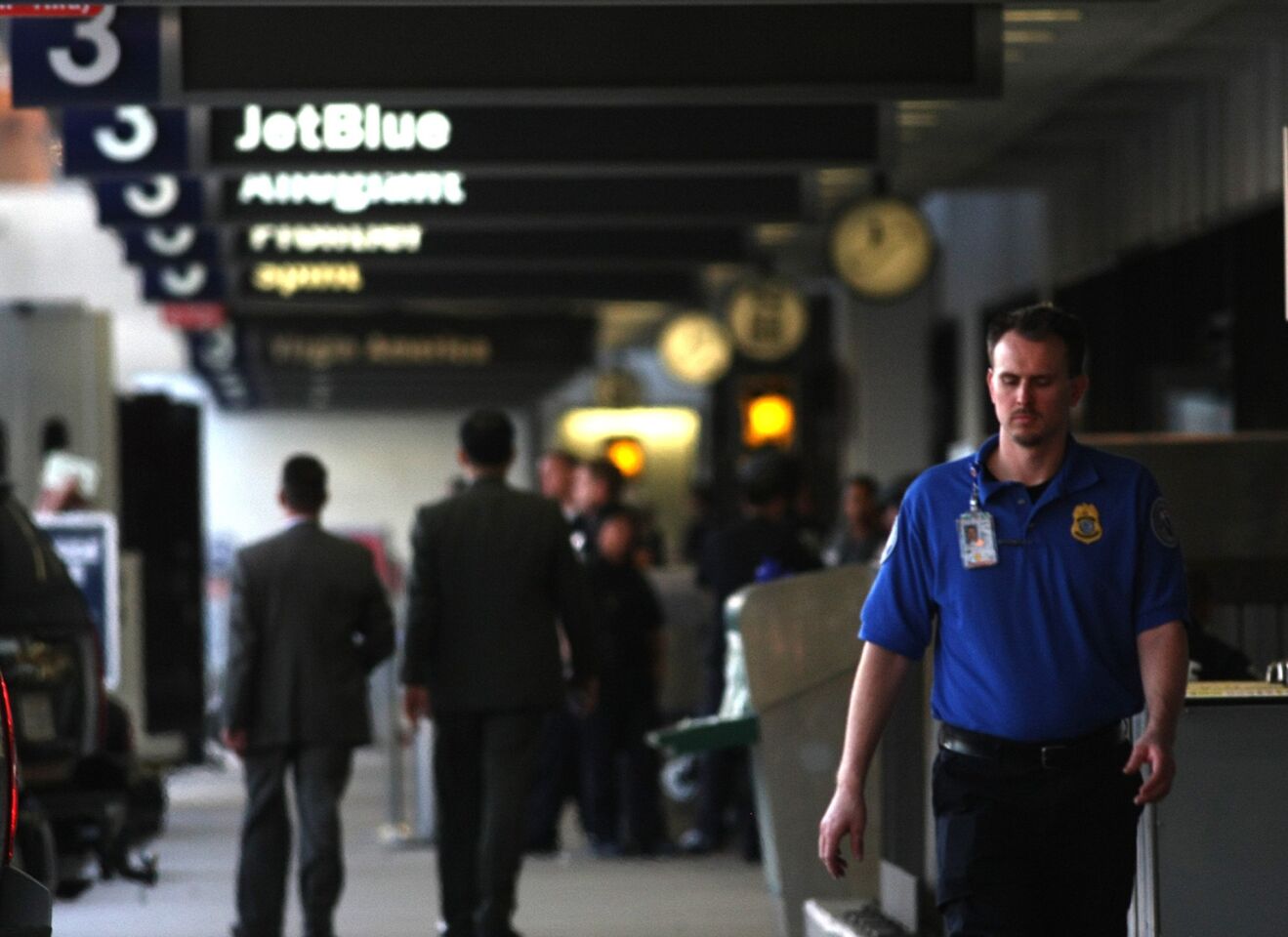 A TSA agent is absorbed in thought as he walks through Terminal 3 at Los Angeles International Airport.