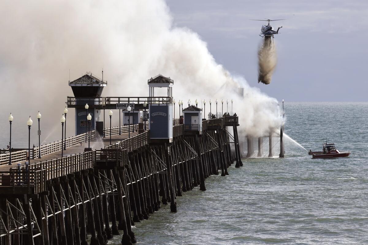A helicopter drops water on the fire at the Oceanside Municipal Pier on April 25.