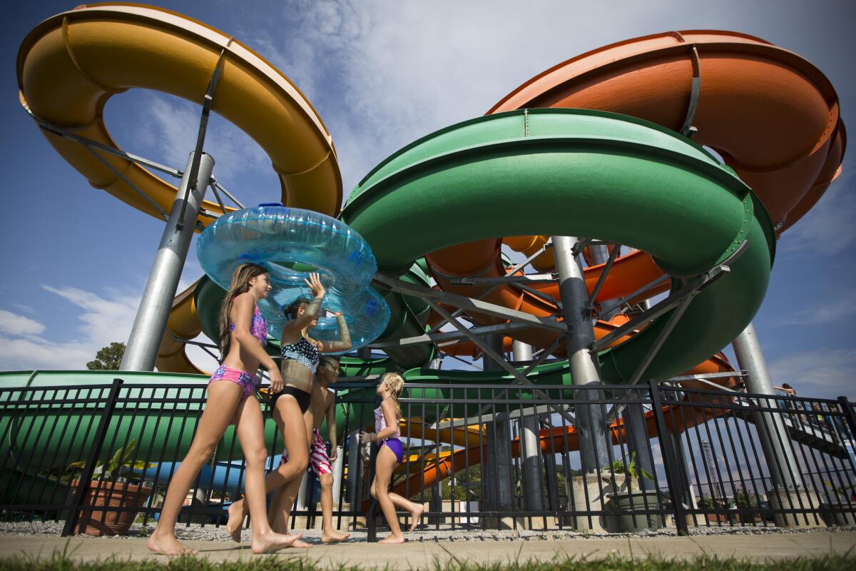Children pass under The Twister water slide at Coney Island amusement park, Sunday, Aug. 30, 2015, in Cincinnati. As the Labor Day closure approaches, revelers eager to enjoy the remaining summer sun have flocked to the park that first opened to serve Cincinnati in 1886. (AP Photo/John Minchillo)