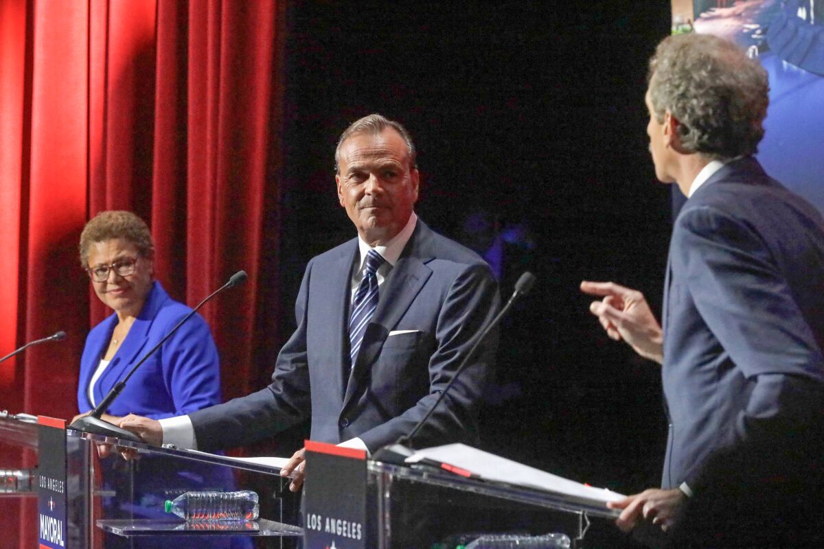 City Atty. Mike Feuer, right, responds to an accusation made by Rick Caruso as U.S. Rep. Karen Bass looks on.