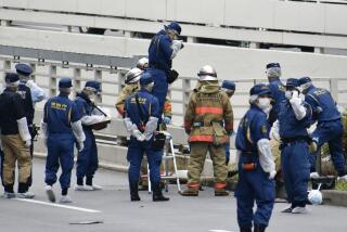 Police and firefighters inspect the scene where a man is reported to set himself on fire, near the Prime Minister's Office in Tokyo, Wednesday, Sept. 21, 2022. The man was taken to a hospital Wednesday, in an apparent protest against a planned state funeral next week for the assassinated former leader Shinzo Abe, officials and media reports said.(Kyodo News via AP)