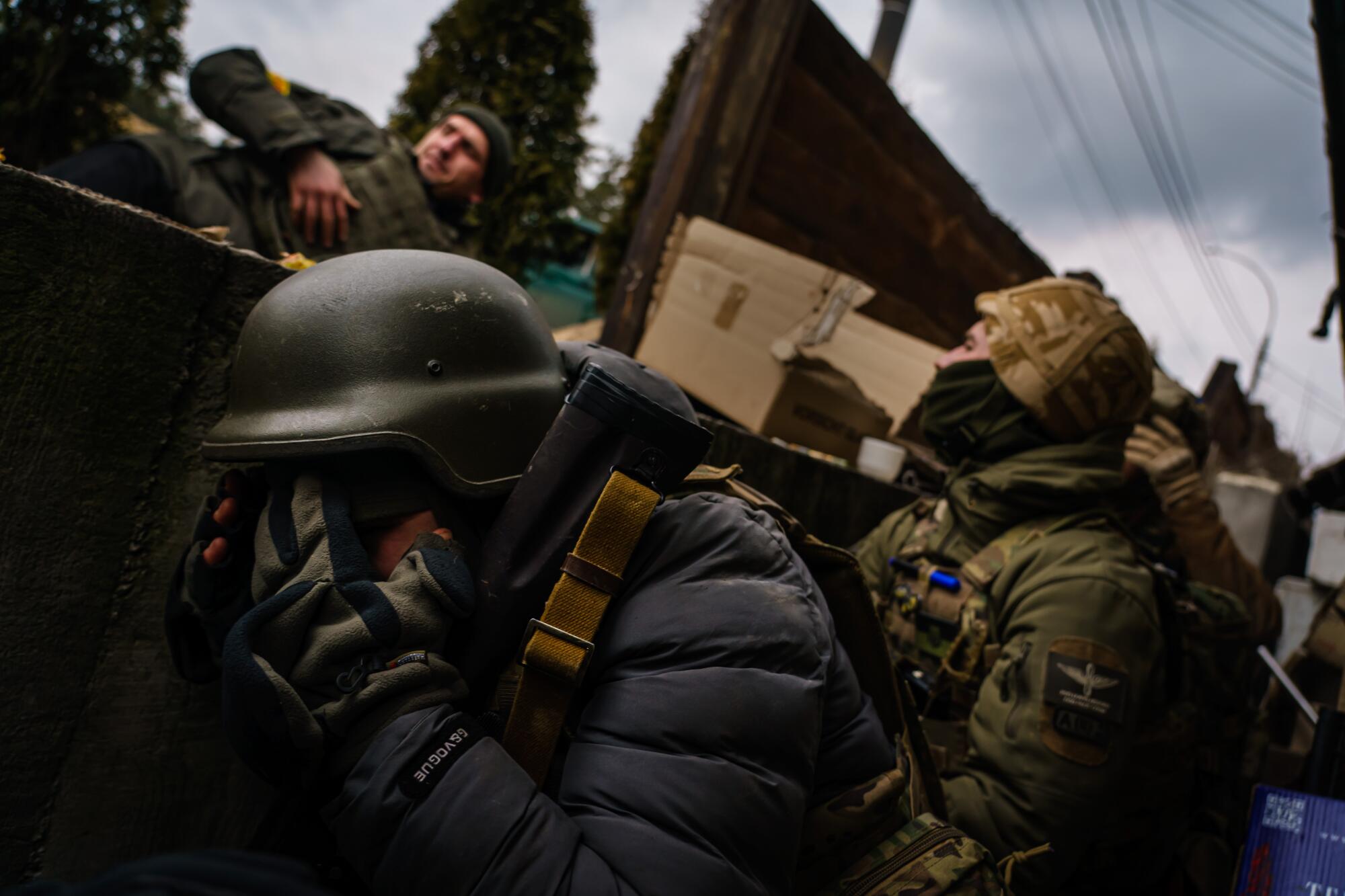 Ukrainian soldiers take cover as they brace for incoming Russian artillery fire at their defensive position