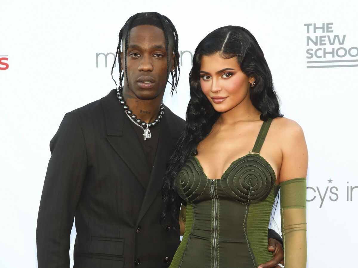 Travis Scott and Kylie Jenner posing in a black suit and a green dress