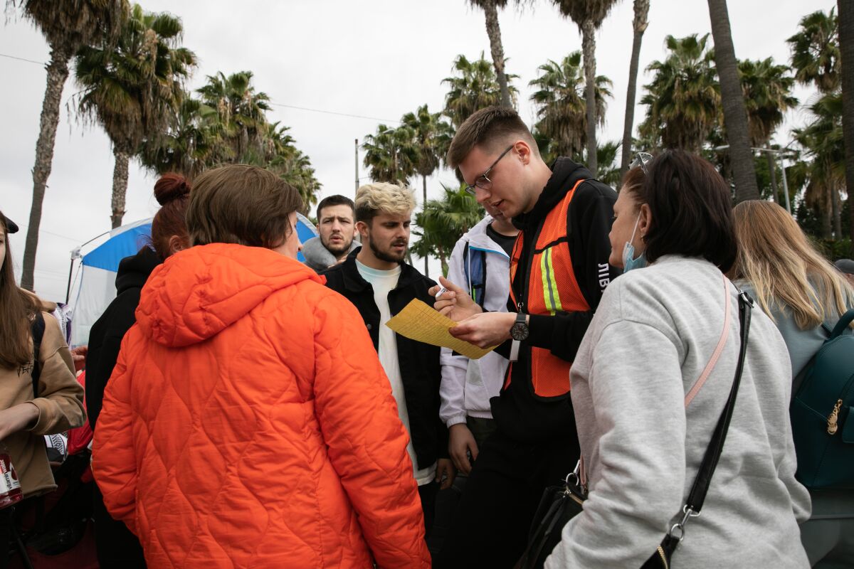 A volunteer reads names of Ukrainian families that are next in line to request protection at the San Diego border