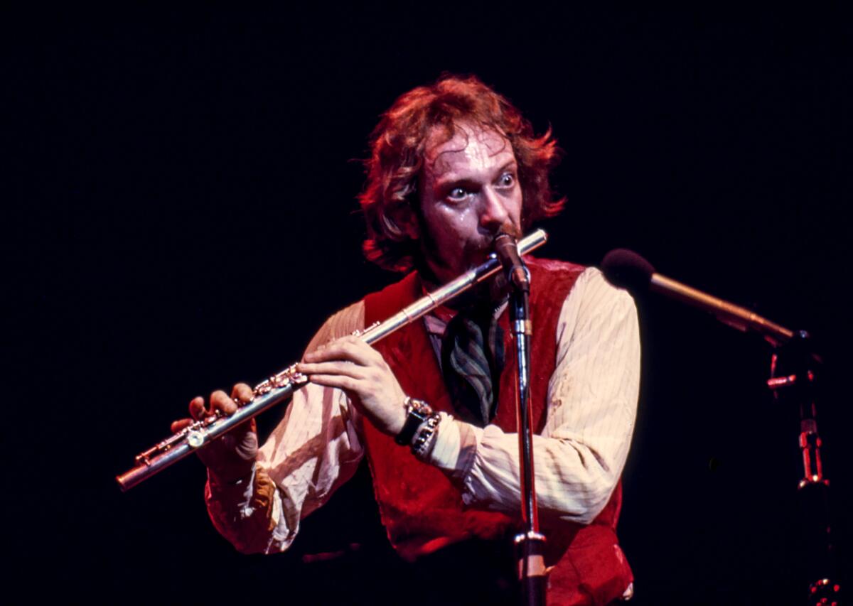 A rock frontman plays a flute onstage