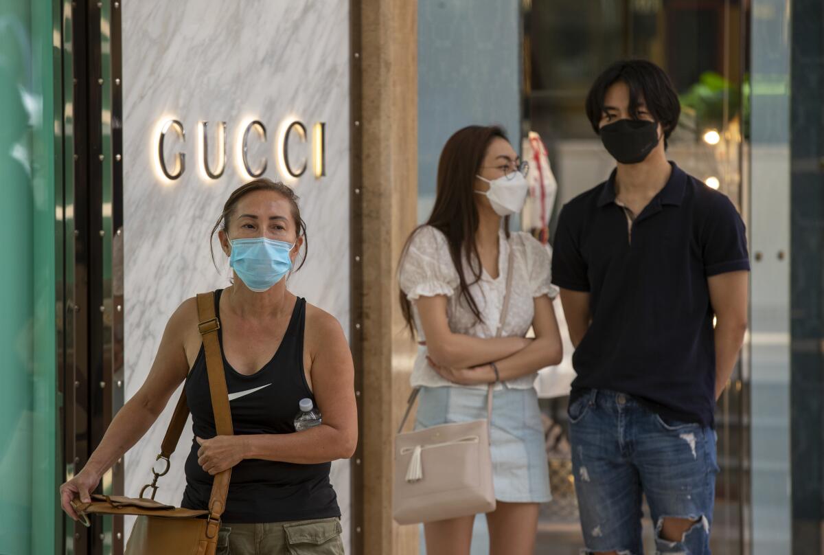 Shoppers wear masks as they wait in line outside at South Coast Plaza in Costa Mesa.