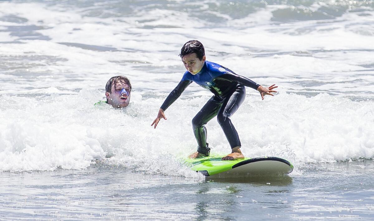 Declan Morrison, 6, from Claremont, rides a wave during a surf camp at Huntington Dog Beach on Tuesday.