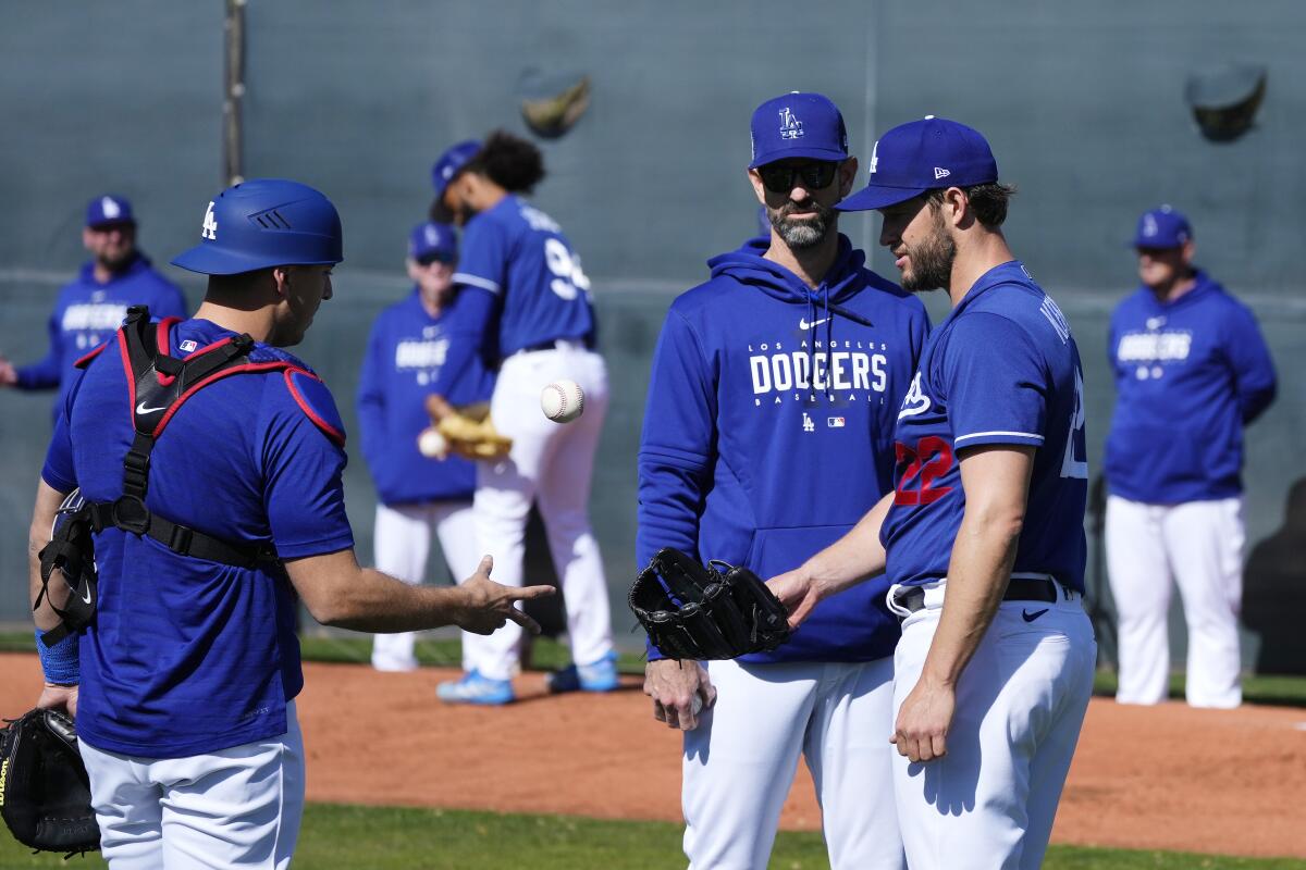 Dodgers catcher Austin Barnes flips the ball back to starting pitcher Clayton Kershaw as pitching coach Mark Prior looks on.
