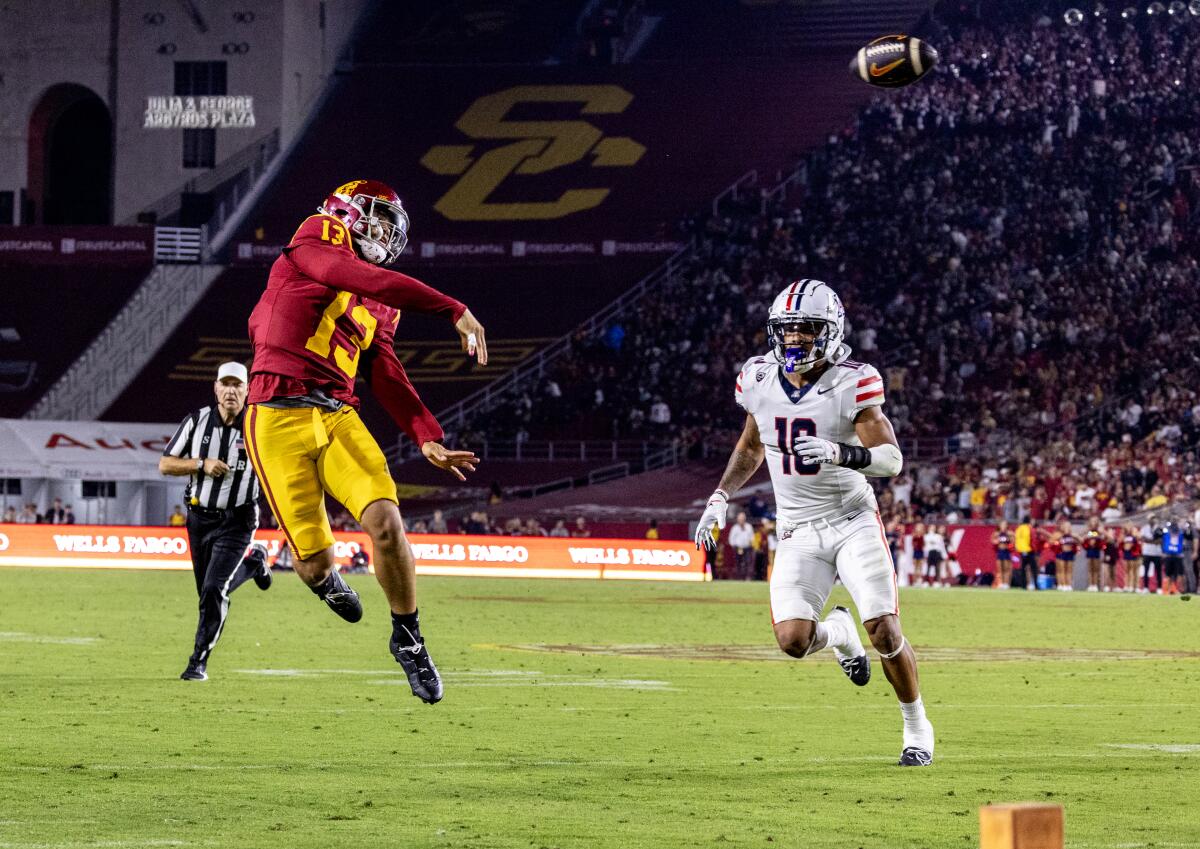 USC quarterback Caleb Williams leaps to throw as Arizona Wildcats linebacker Justin Flowe closes in.