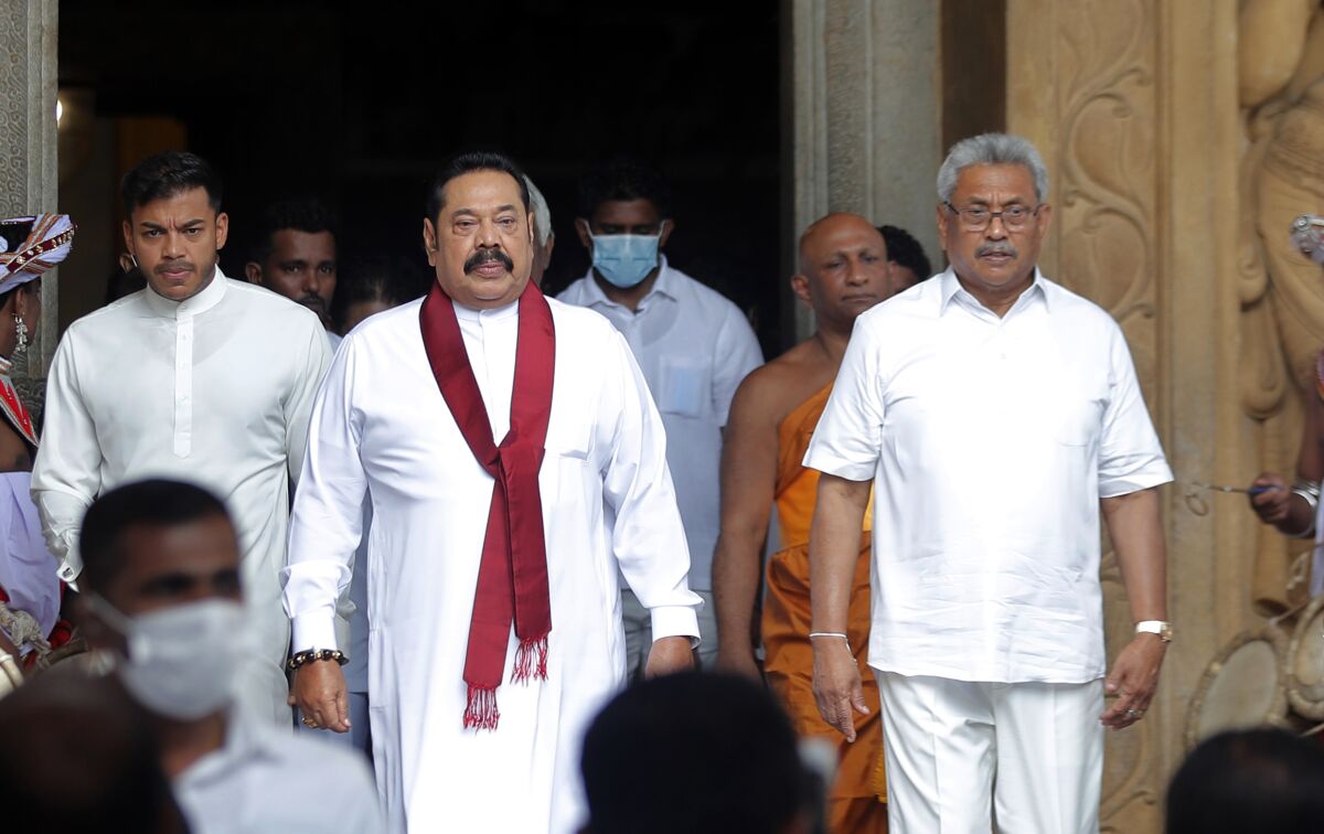 FILE- Sri Lanka's former President Mahinda Rajapaksa, center, leaves with his younger brother, President Gotabaya Rajapaksa, right, after being sworn in as the prime minister at Kelaniya Royal Buddhist temple in Colombo, Sri Lanka, Aug. 9, 2020. Sri Lanka’s president has revoked a days-old state of emergency after huge public protests demanded he resign over the country’s worst economic crisis in memory. (AP Photo/Eranga Jayawardena, File)