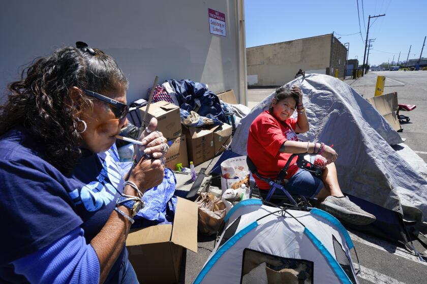 San Diego, CA - April 16: At an encampment in Point Loma on Tuesday, April 16, 2024, in San Diego, CA, Della Infante (l), 59, and Chye Nezzie (r), 45, take a brief break before moving their tent and personal items to the other side of the street because of an abatement notification. Infante has been living on the streets for the past 6 years, and Nezzie for the past 5 years. (Nelvin C. Cepeda / The San Diego Union-Tribune)