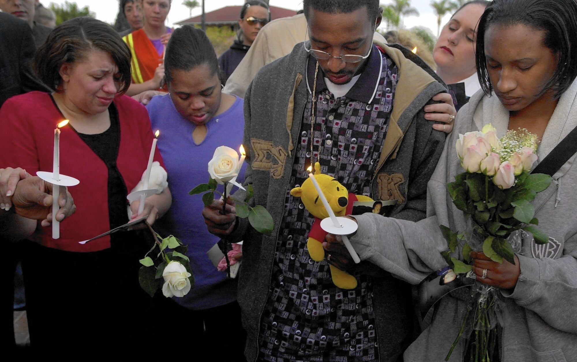 Penny Thompson, friend Renee Brown, Tieray Jones and Tameka Jones hold flowers and candles at a vigil.