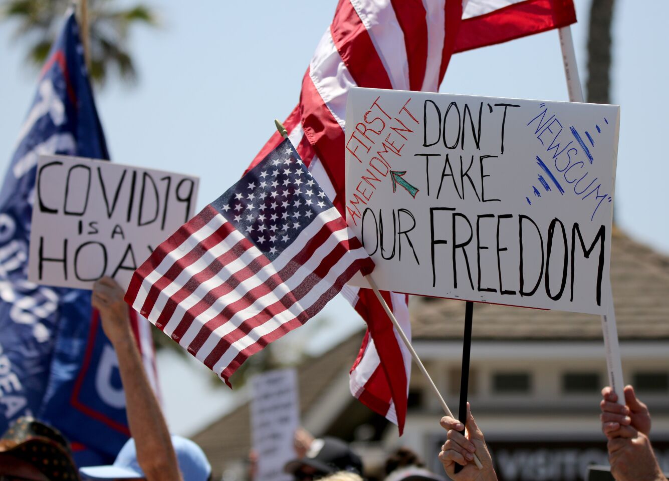 Protesters hold signs up during the protest in Huntington Beach on Friday.