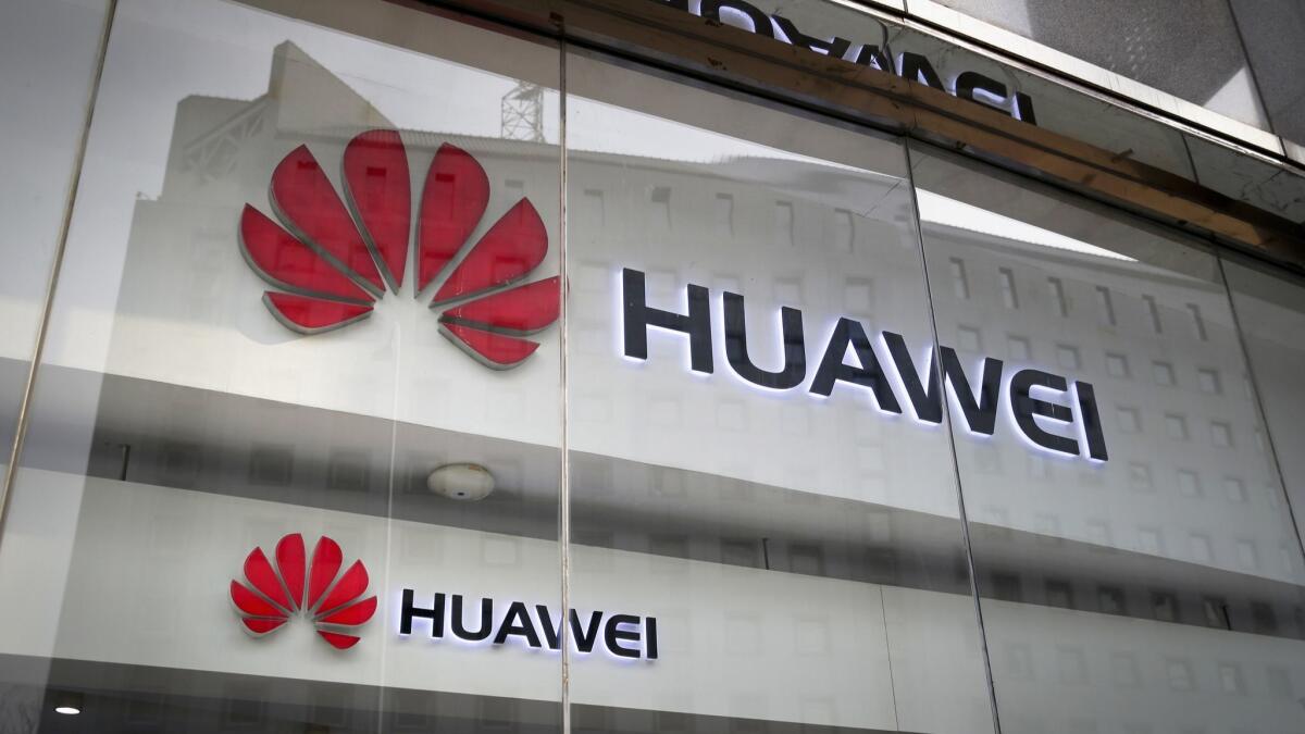 Huawei logos are displayed at its retail shop window reflecting the Ministry of Foreign Affairs office in Beijing.