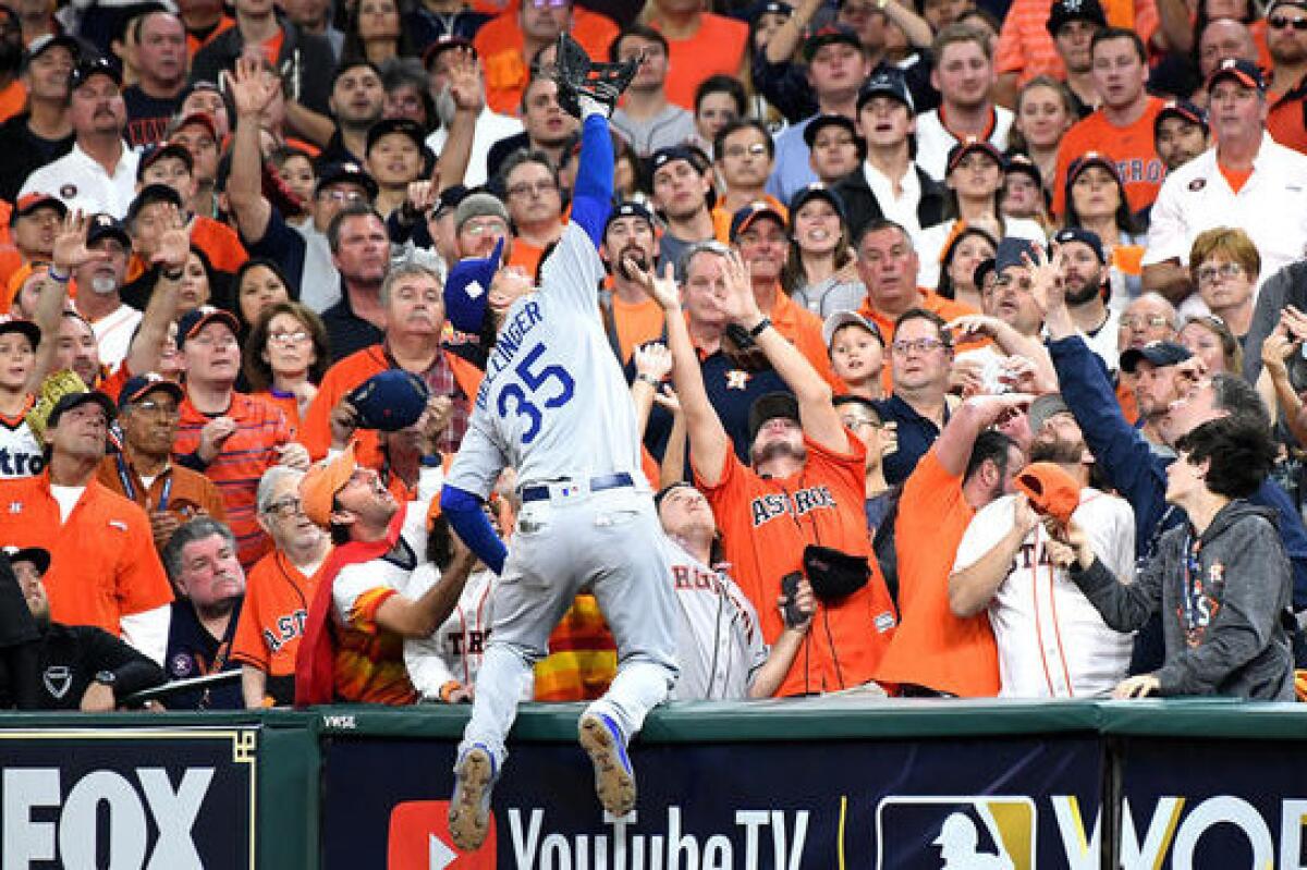 Cody Bellinger goes into the stands to catch a foul ball hit by the Astros' Carlos Correa in the ninth inning. (Wally Skalij / Los Angeles Times)