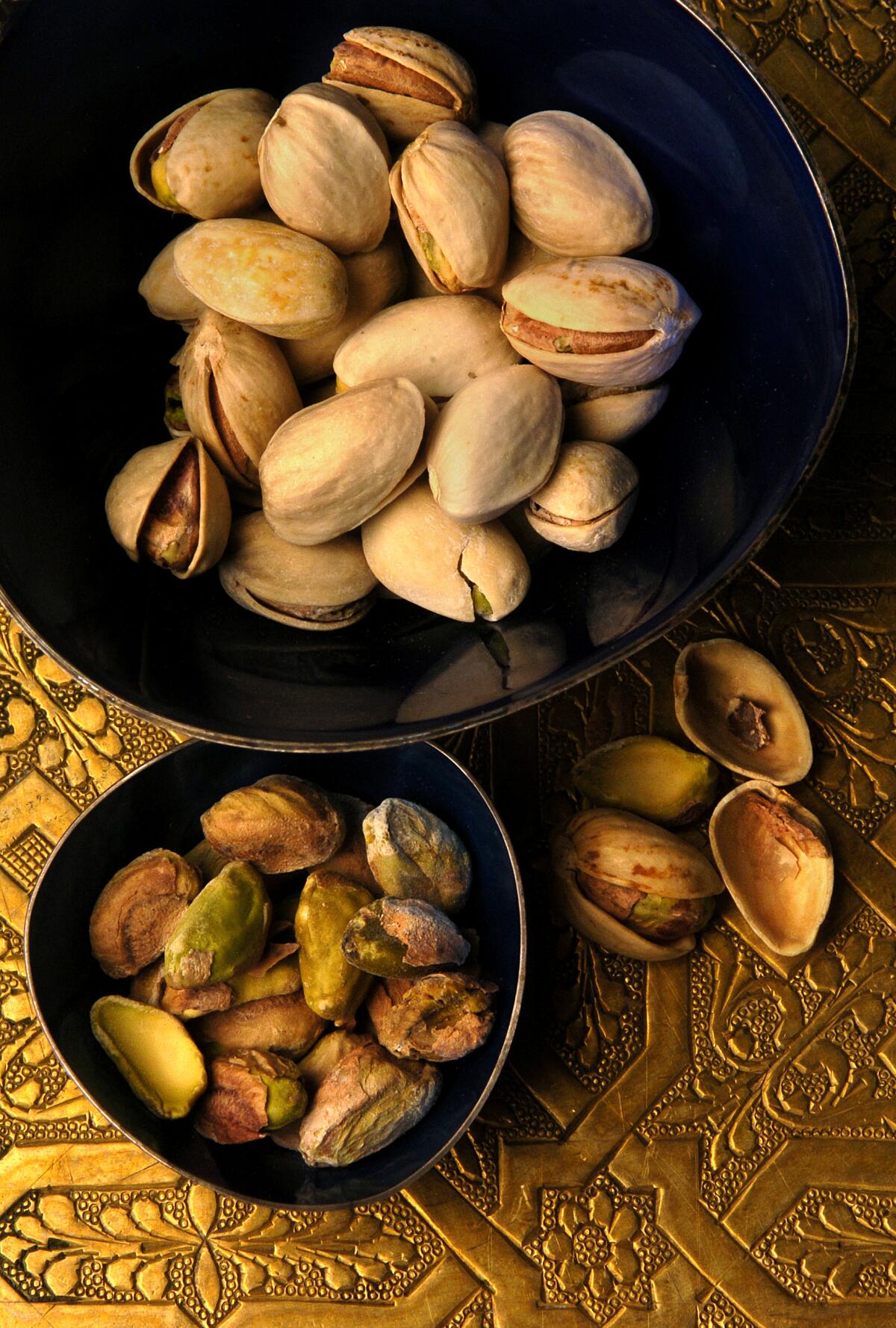 Two bowls hold pistachio nuts.