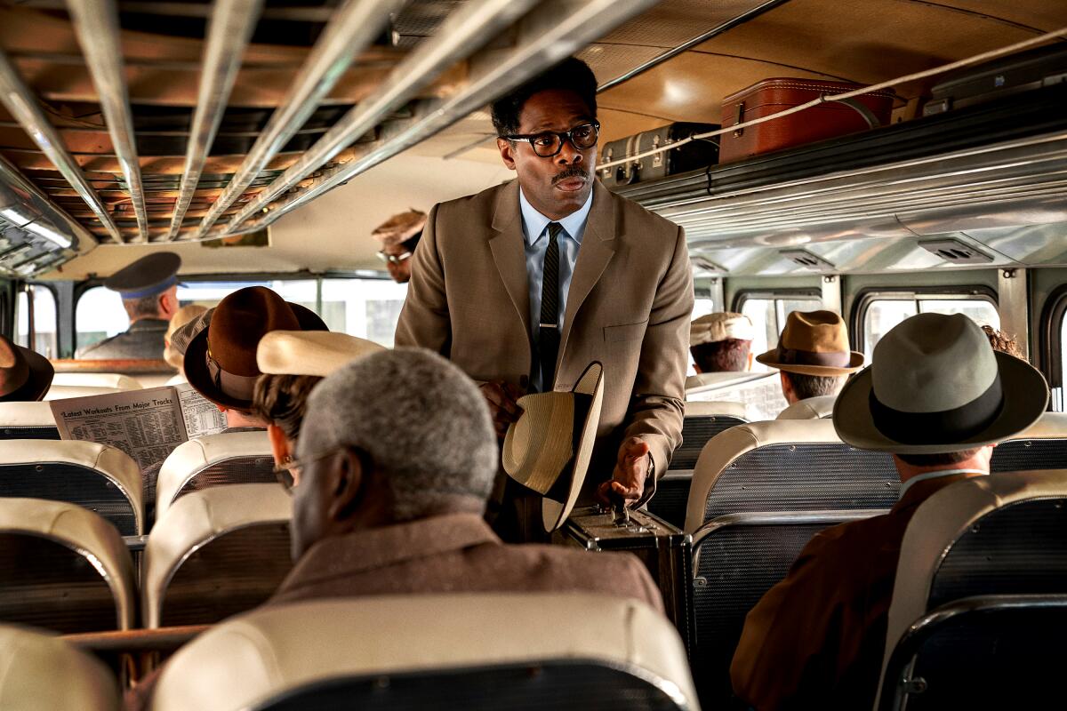 A man in a suit walks down the aisle of a bus in "Rustin."