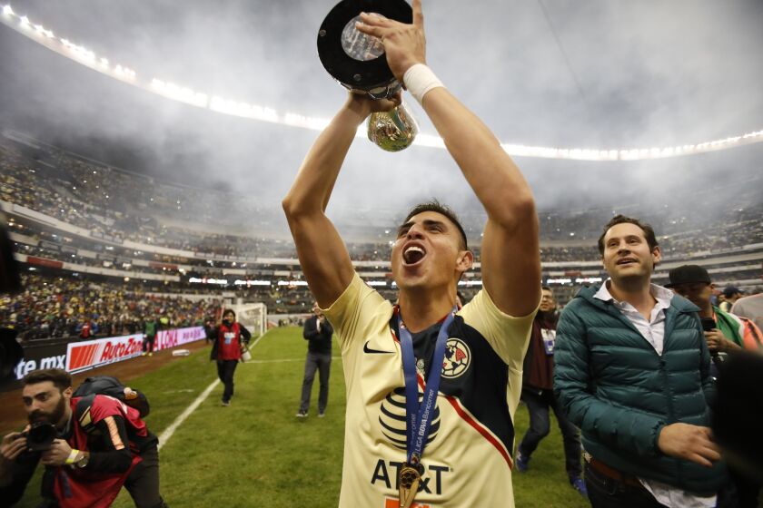 America's Joe Corona holds his team's trophy after defeating Cruz Azul in the final Mexico soccer league championship match at Azteca stadium in Mexico City, Sunday, Dec. 16, 2018. (AP Photo/Rebecca Blackwell)