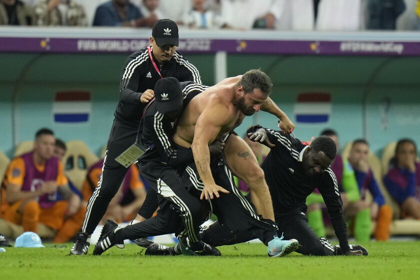 A pitch invader is tackled by security during the World Cup quarterfinal soccer match between the Netherlands and Argentina, at the Lusail Stadium in Lusail, Qatar, Friday, Dec. 9, 2022. (AP Photo/Francisco Seco)