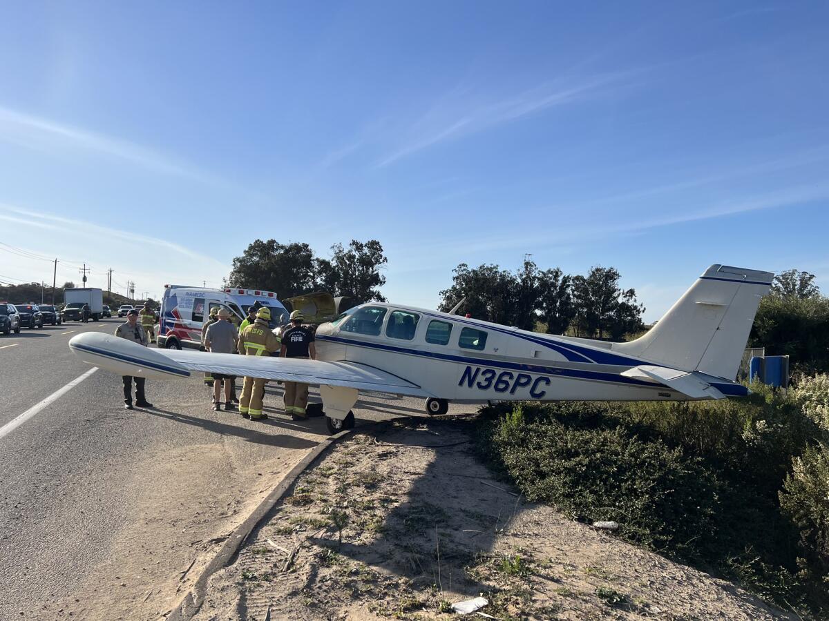 A small plane straddles the side of a roadway. 