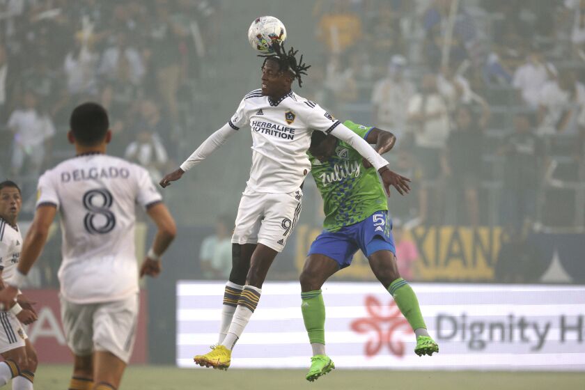 LA Galaxy forward Kévin Cabral, center, heads the ball next to Seattle Sounders' Nouhou