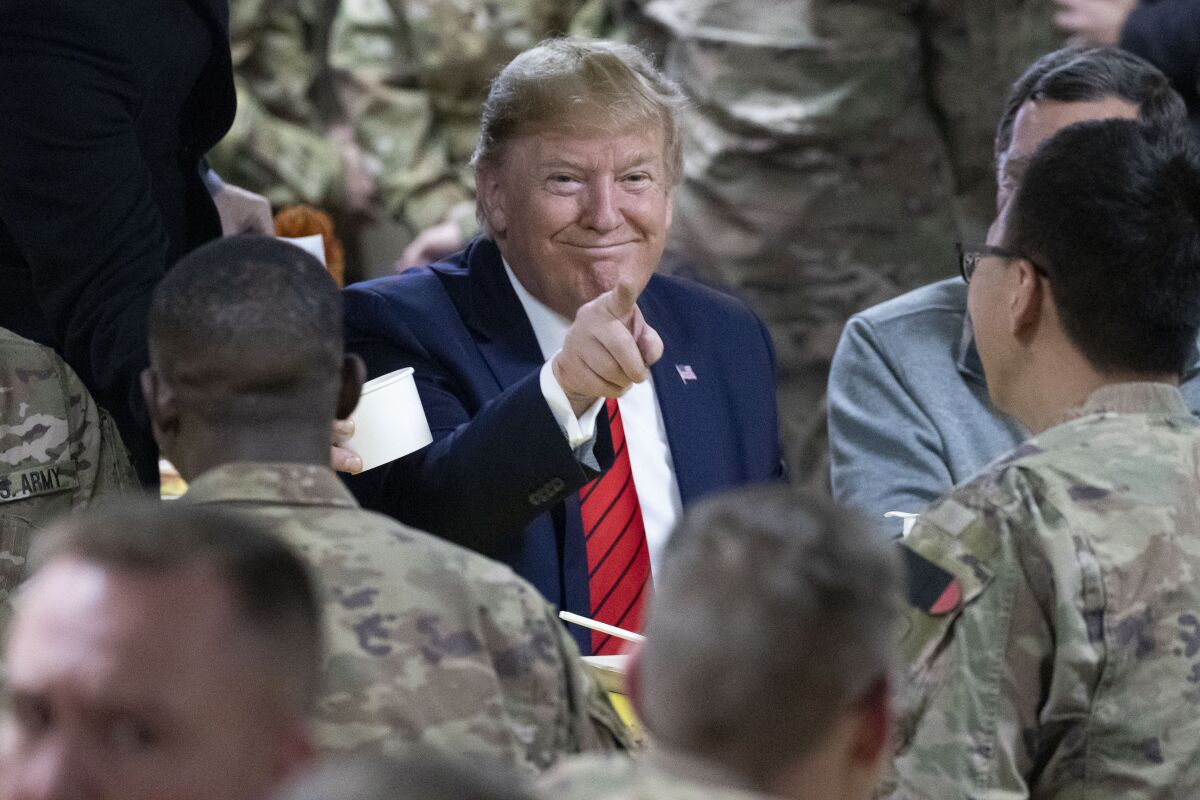 President Trump smiling and pointing toward the camera at Bagram Airfield in Afghanistan on Nov. 28, 2019. In the foreground, U.S. soldiers stand before him.