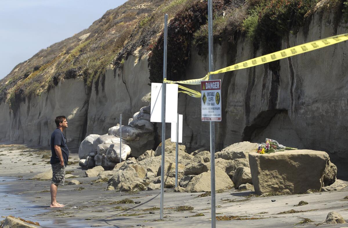 A man looks at looks at the debris left from the fatal bluff collapse last August at Grandview Beach in Encinitas
