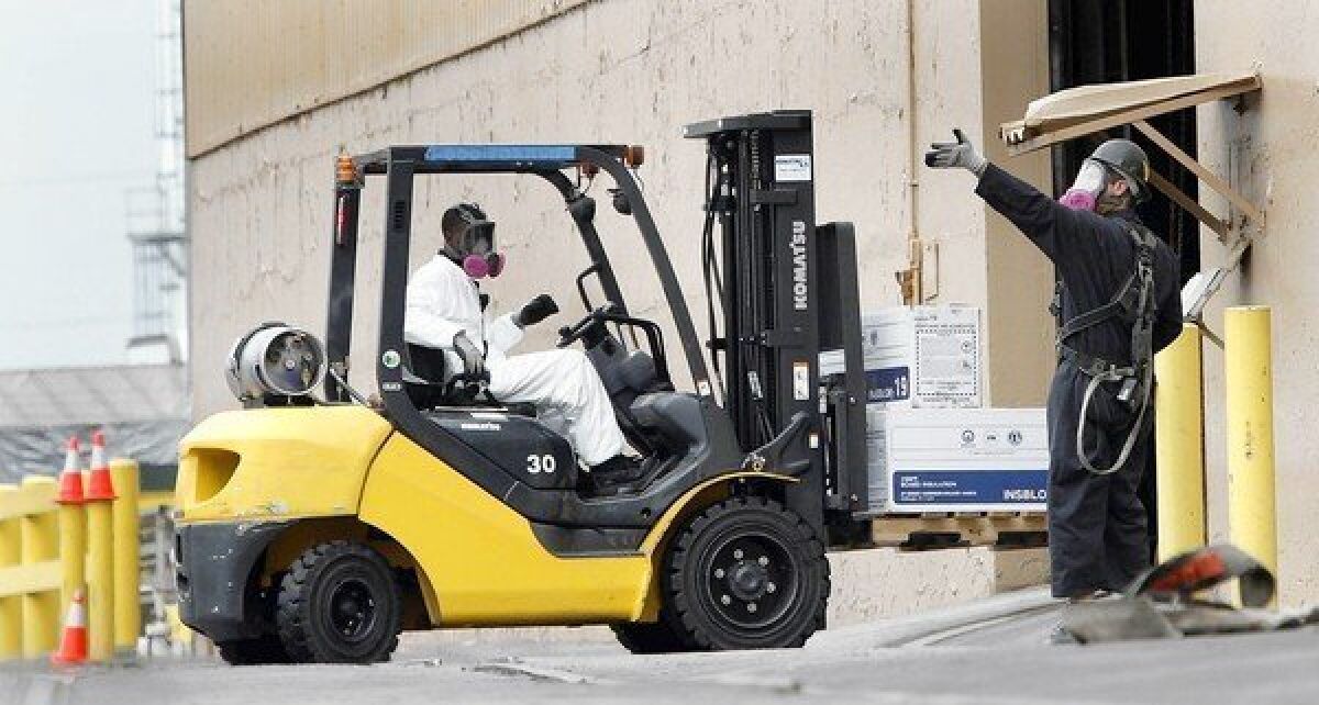 Wearing breathing devices, employees move boxes at the Exide battery recycling plant in Vernon. State officials suspended operations at the plant in April, citing emissions of arsenic as a health risk to 110,000 people in surrounding communities. The plant has also discharged harmful quantities of lead.
