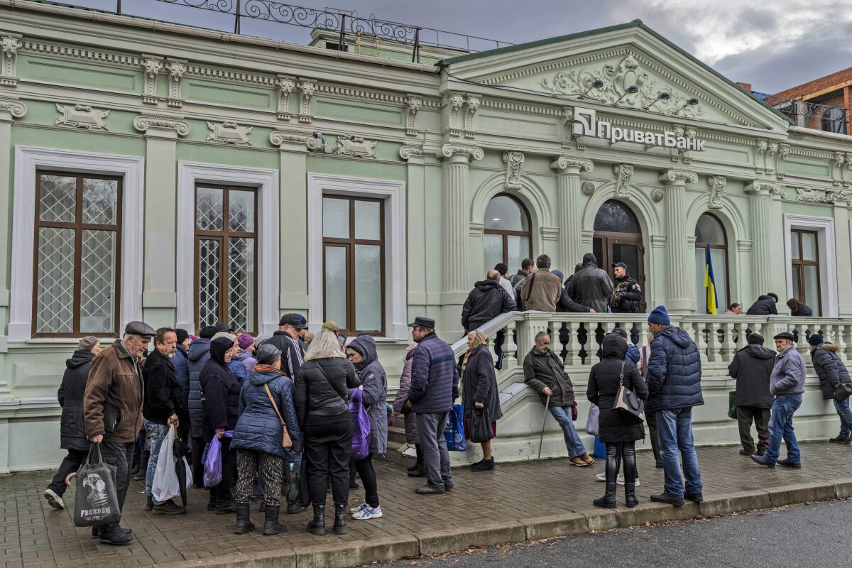 FILE - Residents queue at a bank branch in Kherson, southern Ukraine, Nov. 21, 2022. Even as Ukraine celebrates recent battlefield victories, its government faces a looming challenge on the financial front: how to pay the enormous cost of the war effort without triggering out-of-control price spikes for ordinary people or piling up debt that could hamper postwar reconstruction. (AP Photo/Bernat Armangue, File)