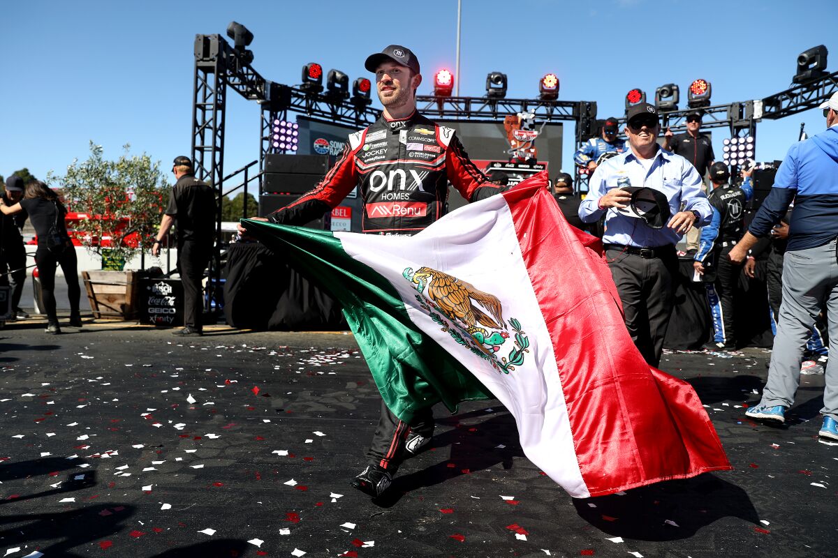Mexican NASCAR driver Daniel Suarez holds a Mexican flag 