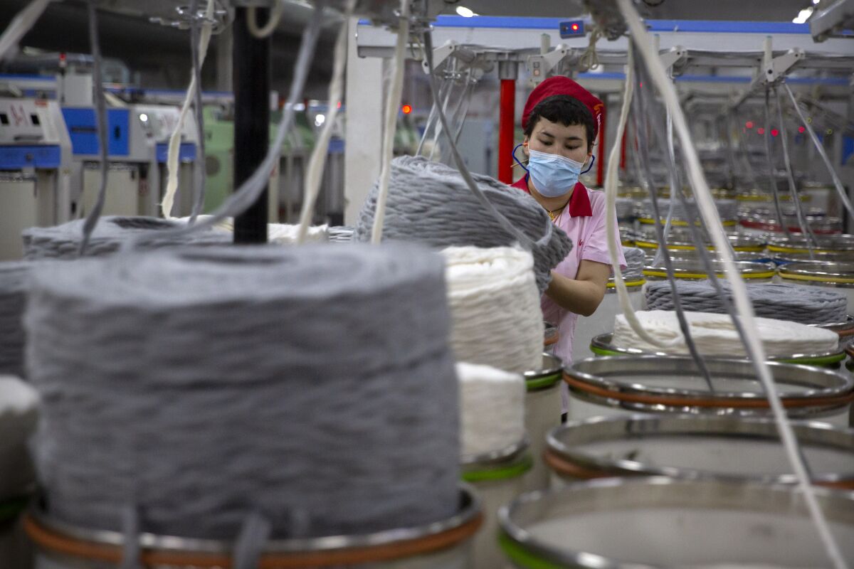 A worker gathers cotton yarn at a textile manufacturing plant, as seen during a government organized trip for foreign journalists, in Aksu in western China's Xinjiang Uyghur Autonomous Region, Tuesday, April 20, 2021. China on Friday, Dec. 17, 2021 said it would "take all necessary measures" to safeguard its institutions and enterprises after the U.S. Senate passed a new law barring imports from the Xinjiang region unless businesses can prove they were produced without forced labor. (AP Photo/Mark Schiefelbein)