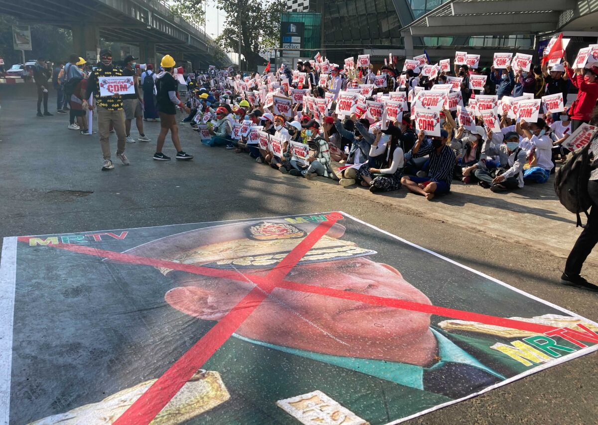 A large image of Senior Gen. Min Aung Hlaing on a street has an X across it.