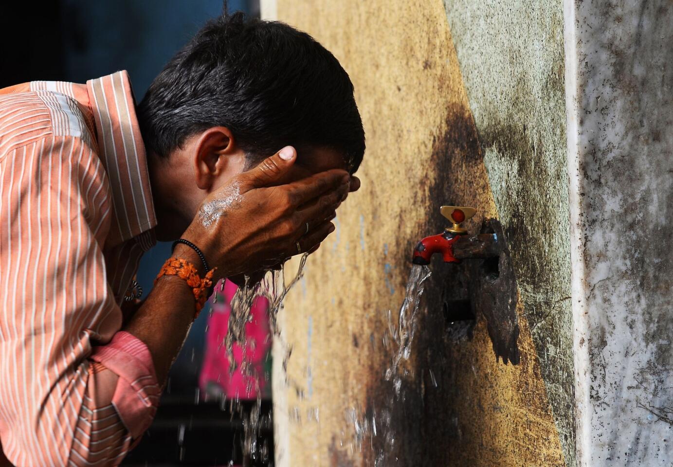 An Indian man washes his face at a roadside tap in New Delhi. Hospitals in India battled to treat victims of a blistering heat wave that has claimed nearly 1,500 lives in just over a week -- the highest number recorded in two decades.