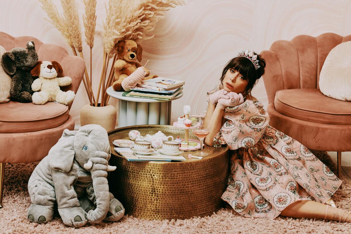 A woman in a patterned dress sits on the floor in a children's room.