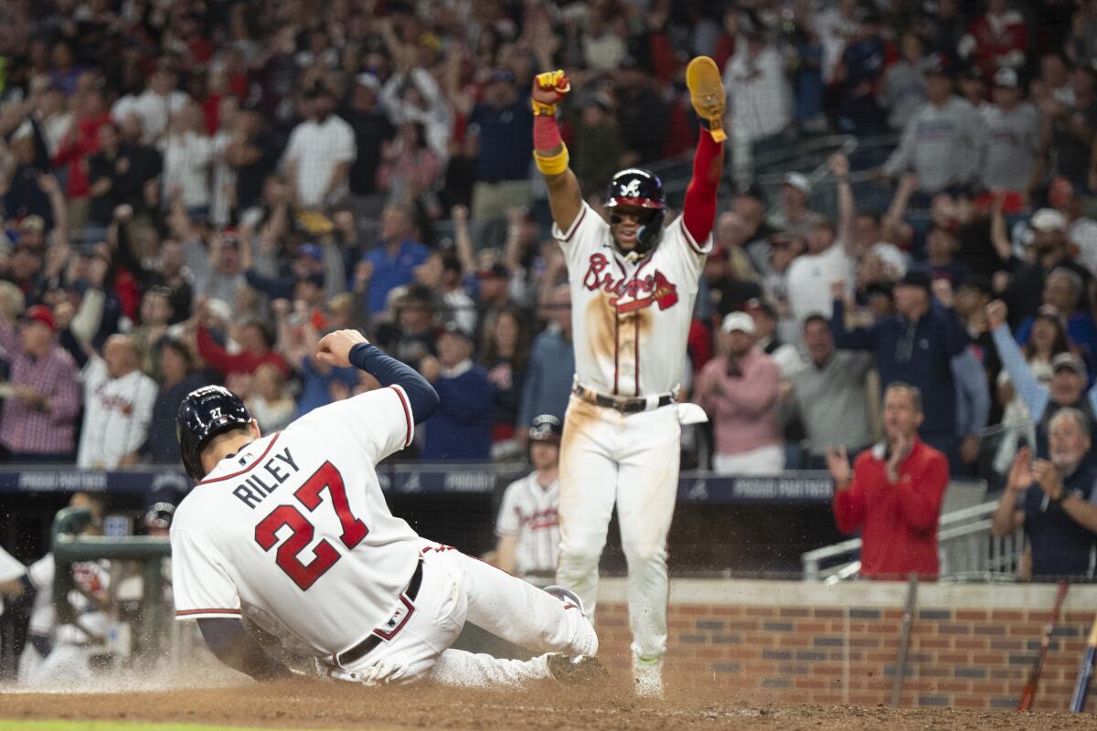 Atlanta Braves Ronald Acuna Jr. and Austin Riley score on a single hit by Travis d'Arnaud in the third inning of a baseball against the New York Mets, Sunday, Oct. 2, 2022, in Atlanta. (AP Photo/Hakim Wright Sr.)