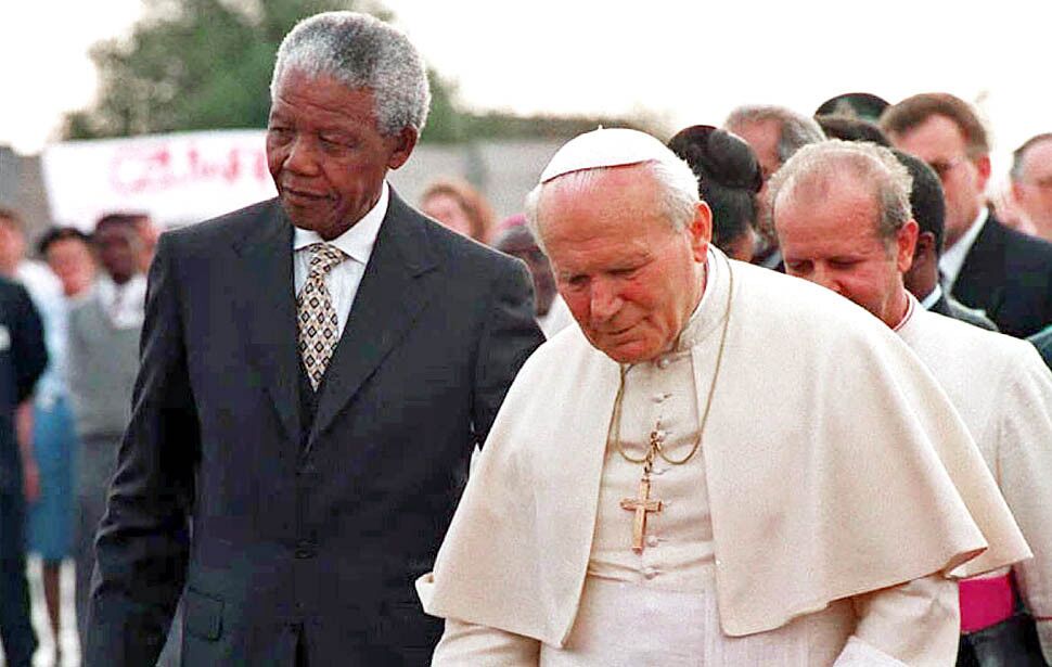 President Nelson Mandela walks with Pope John Paul II after the pontiff's arrival at Johannesburg airport September 16,1995. This was the Pope's first official visit to South Africa.