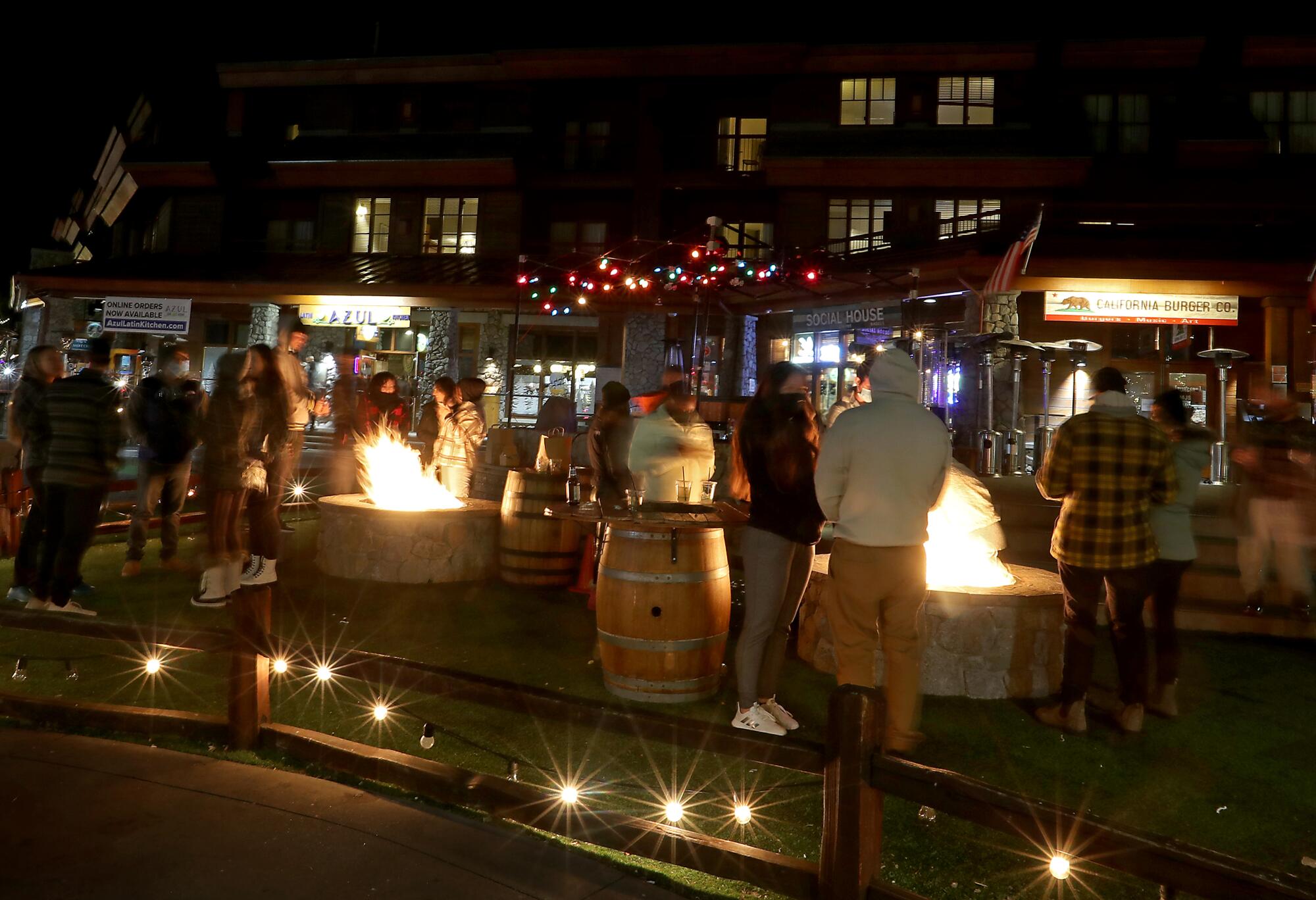 People hang out beside bonfires in a shopping and dining area of South Lake Tahoe.