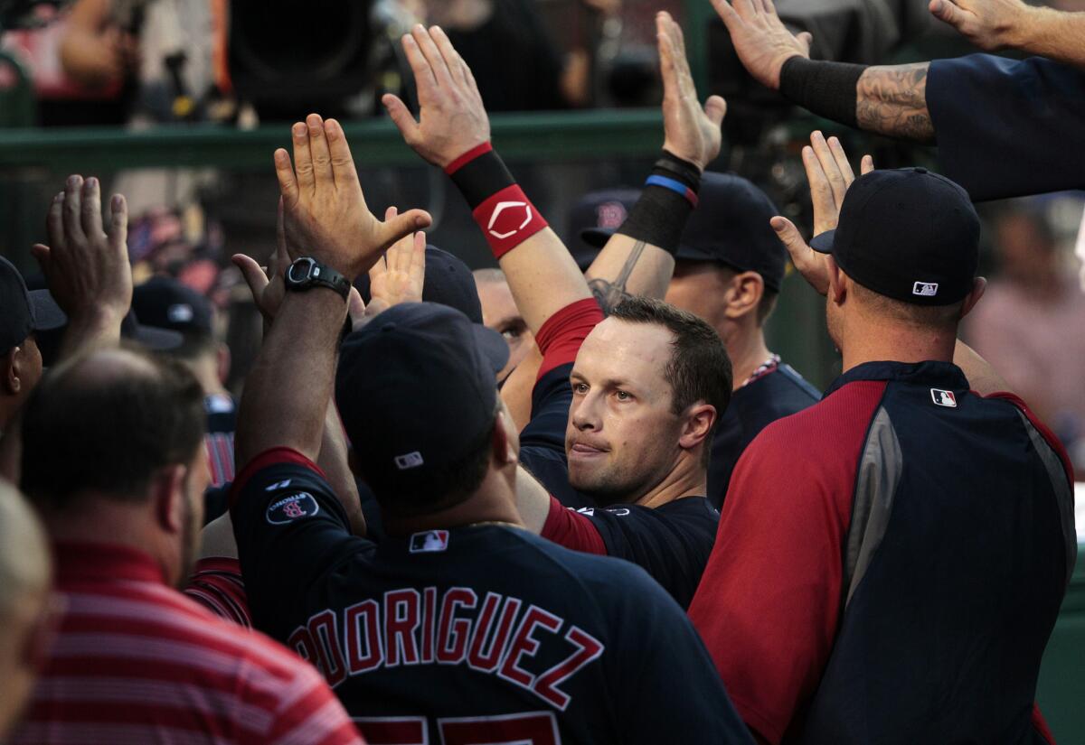 Red Sox outfielder Daniel Nava gets high-fives in the dugout after scoring in the second inning against the Angels on July 5, 2013.