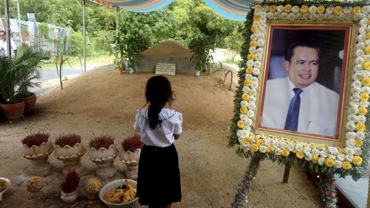 A girl stands beside a portrait of activist Kem Ley at his grave in Ang Takok, Cambodia.
