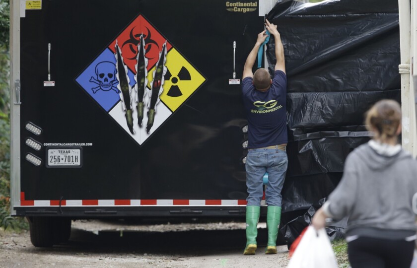 A hazardous materials worker puts up a plastic sheet before starting to clean the apartment of a hospital worker Sunday.