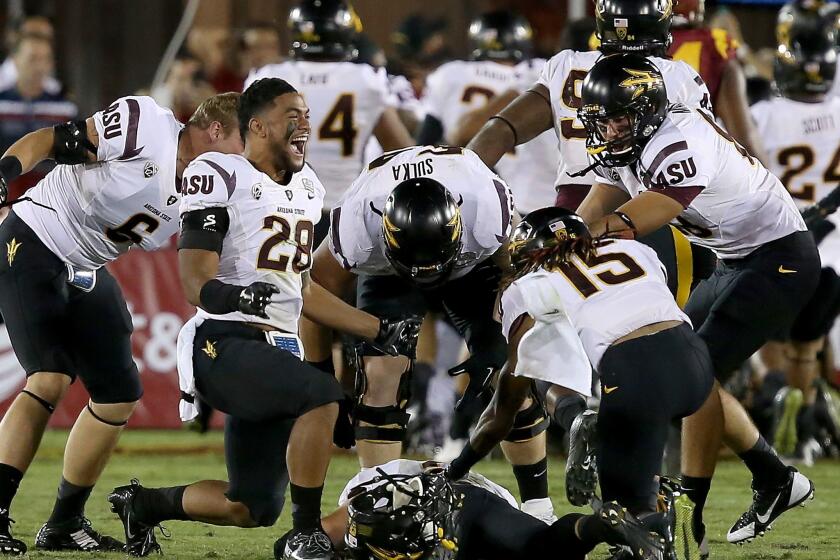 Arizona State quarterback Mike Bercovici (on ground) is about to be engulfed by teammates after throwing a 46-yard touchdown pass on the final play of the game to beat USC, 38-34, on Saturday night at the Coliseum.