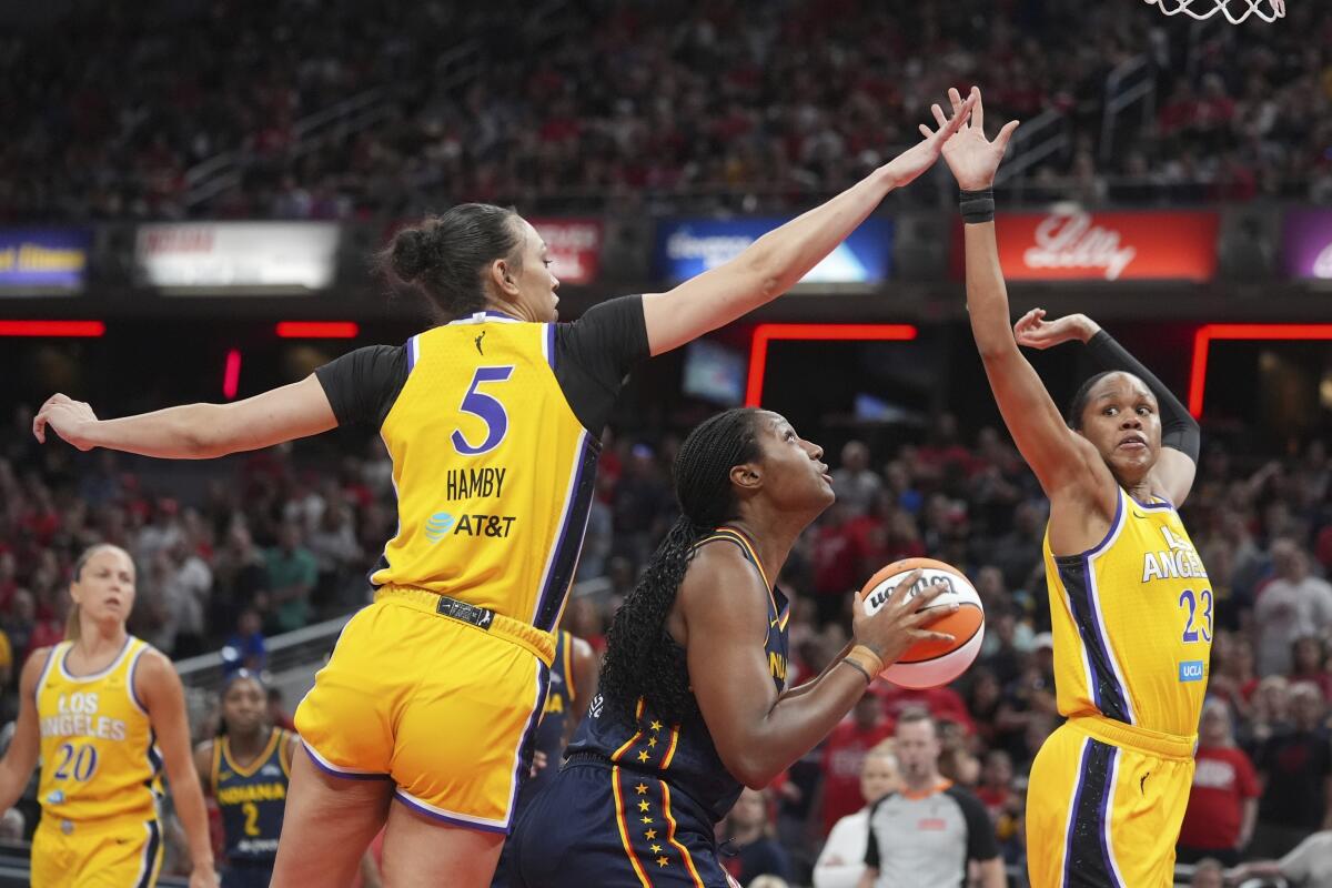 Fever forward Aliyah Boston, center, looks to shoot as Sparks defender Dearica Hamby, left, and Azura Stevens defend her.