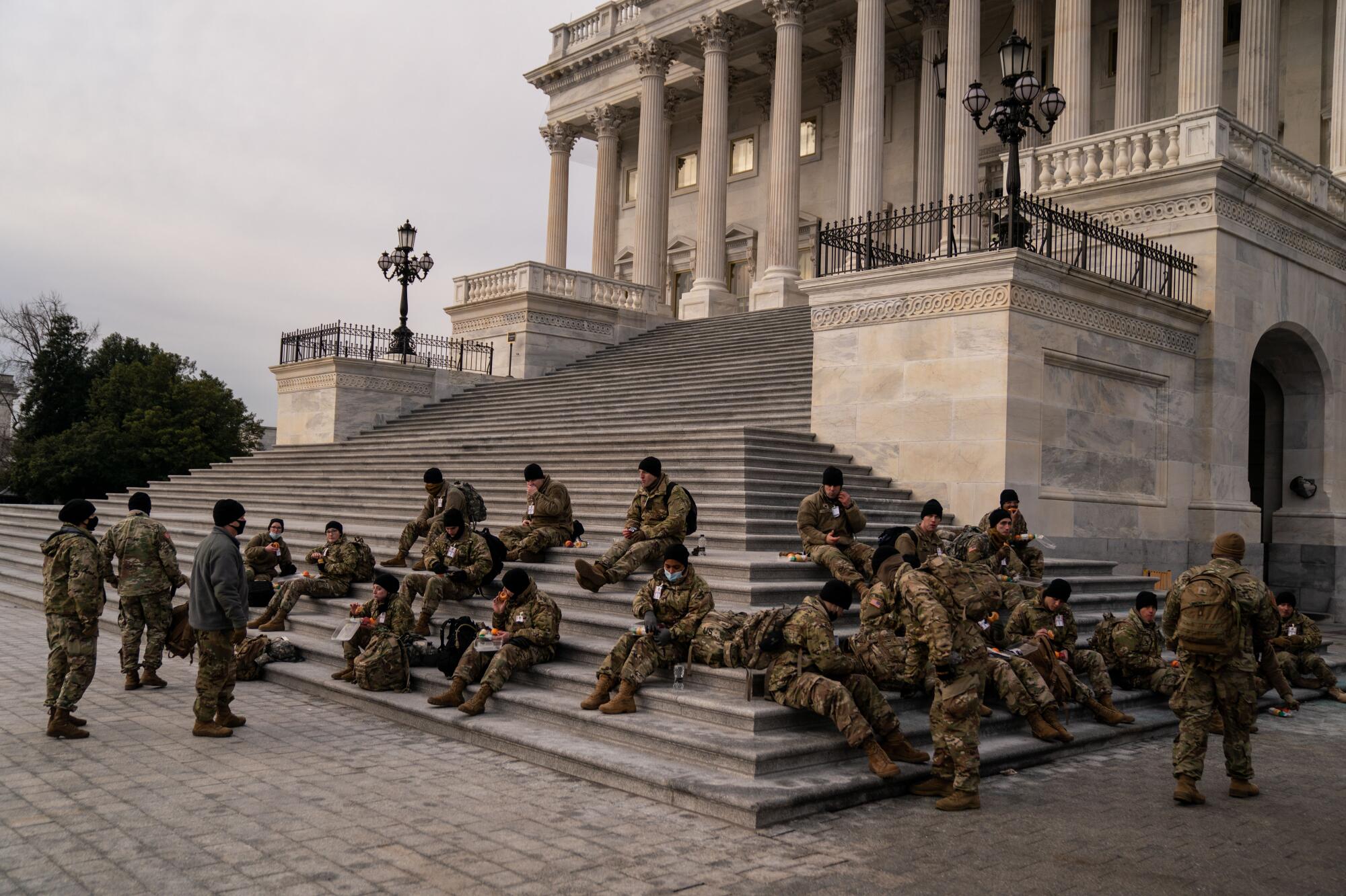 National Guard members sit on the steps to the U.S. Capitol as they eat breakfast.