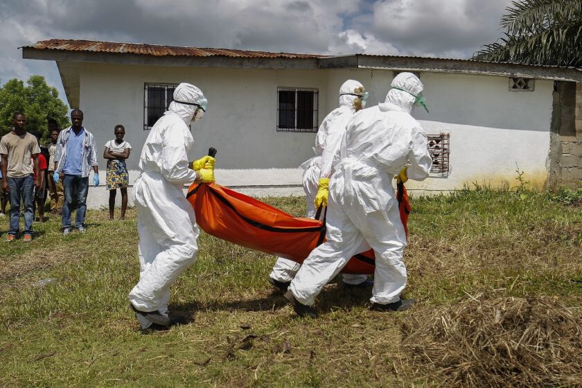 A Liberian Red Cross burial team retrieves the body of a suspected victim of Ebola in Banjor, on the outskirts of Monrovia, Liberia.