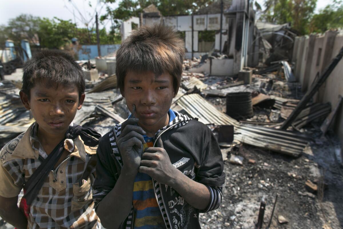 Two boys stand near their destroyed home April 5 in Meiktila, Myanmar. Recent sectarian violence between Buddhists and Muslims has left dozens dead, and Human Rights Watch said Monday that the attacks on Rohingya Muslims amount to crimes against humanity.